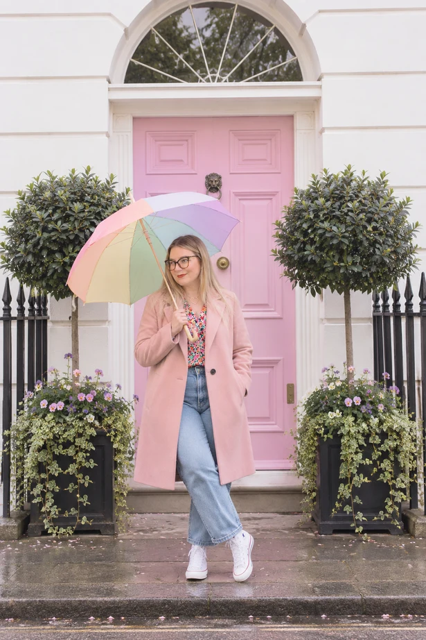 Kristyn holding a colourful umbrella outside a pink front door